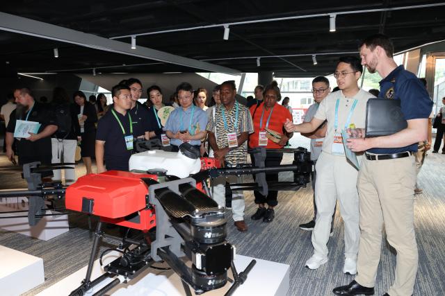 (260728) -- SHENZHEN, July 28, 2026 (Xinhua) -- Attendees of the 2026 APEC Ministerial Meeting on Forestry learn about a drone at a robotics zone in Shenzhen, south China's Guangdong Province, July 28, 2026. The meeting was held in Shenzhen from July 27 to 28. (Xinhua/Liang Xu)