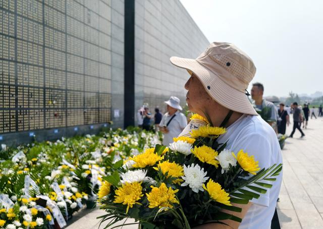 (260728) -- TANGSHAN, July 28, 2026 (Xinhua) -- A citizen presents a bunch of flowers in front of a memorial wall inscribed with names of the victims at the Tangshan Earthquake Memorial Park in Tangshan, north China's Hebei Province, July 28, 2026. This year marks the 50th anniversary of the Tangshan Earthquake, a magnitude-7.8 quake that struck the city on July 28, 1976, taking the lives of more than 240,000 people and destroying virtually all buildings in the city.
   Crowds of people visited the Tangshan Earthquake Memorial Park on Tuesday to mourn and remember the victims in the devastating disaster. (Xinhua/Yang Shiyao)