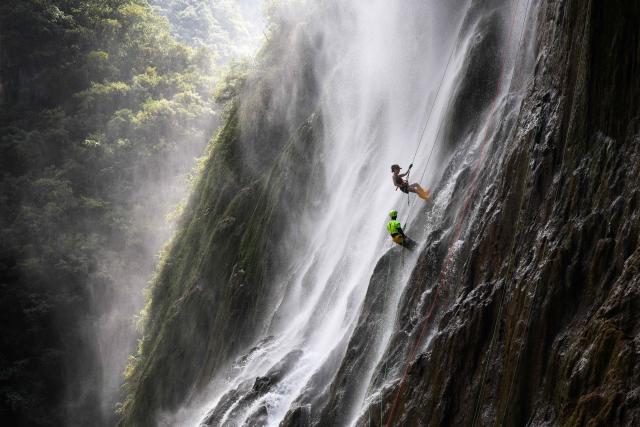 (260730) -- BEIJING, July 30, 2026 (Xinhua) -- A tourist experiences waterfall rappelling under the guidance of a staff member at a scenic area in Huangping County, Qiandongnan Miao and Dong Autonomous Prefecture, southwest China's Guizhou Province, July 29, 2026. The waterfall rappelling here has attracted tourists for cool relief and exhilarating experience. (Xinhua/Yang Wenbin)
