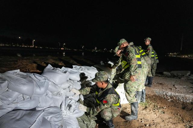 (260730) -- DUNHUANG, July 30, 2026 (Xinhua) -- Militiamen stack sandbags to fortify the embankment along the Danghe River in Dunhuang, northwest China's Gansu Province, July 29, 2026. The water level of the Danghe River, which runs through Dunhuang City in northwest China's Gansu Province, rose rapidly following days of heavy rainfall and increased inflows from upstream. Local personnel in Dunhuang quickly mobilized for flood control and relief operations. (Xinhua/Lang Bingbing)