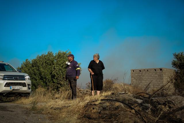(260730) -- CRETE, July 30, 2026 (Xinhua) -- A firefighter and a resident check an area affected by a wildfire in Rethymno on the island of Crete, Greece, July 29, 2026. Two firefighters lost their lives while battling a fast-moving wildfire in Rethymno on the Greek island of Crete on Wednesday, as gale-force winds fueled the blaze across a front stretching more than 15 kilometers. (Photo by Rapanis Spiros/Xinhua)