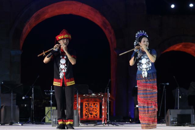 (260730) -- JERASH, July 30, 2026 (Xinhua) -- Two Chinese artists perform nose flute during the 40th Jerash Festival of Culture and Arts at the ancient Roman Hippodrome in Jerash, Jordan, July 29, 2026. China's traditional music and intangible cultural heritage took center stage on Wednesday at the 40th Jerash Festival of Culture and Arts, one of the Middle East's largest cultural events.
  The performance featured traditional Chinese instruments, including the erhu, bamboo flute, suona and pipa, alongside intangible cultural heritage elements such as nose-flute performance and leaf-blowing music.
  An accompanying exhibition in the festival's international cultural area showcased Hainan's intangible cultural heritage, including coconut-shell carving, grass weaving, collage art and traditional stone-rubbing techniques. (Photo by Mohammad Abu Ghosh/Xinhua)