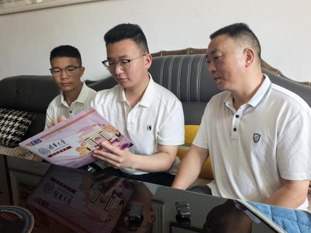 (260730) -- GUIYANG, July 30, 2026 (Xinhua) -- Hu Haoran (C) opens the envelope of the admission letter from Tsinghua University at home in Bijie City, southwest China's Guizhou Province, July 27, 2026. TO GO WITH "Feature: Relocation policy lights up educational path for youth in SW China" (Xinhua)