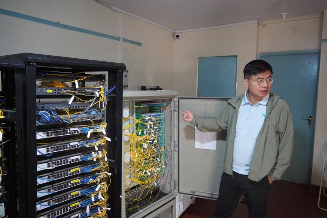 (260730) -- DAR ES SALAAM, July 30, 2026 (Xinhua) -- Zhou Tao introduces the system configuration at a community network access center, which provides fiber-optic internet services to more than 18,000 households in Kibera, Nairobi, Kenya, July 10, 2026. TO GO WITH XINHUA HEADLINES ON JULY 30, 2026. (Xinhua/Lu Zexin)