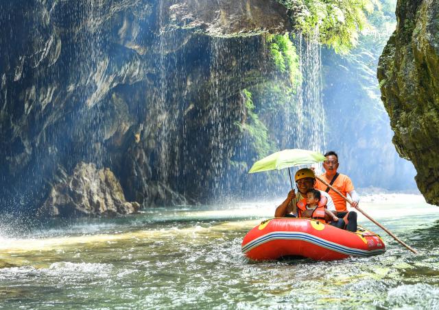 (260730) -- HUANGPING, July 30, 2026 (Xinhua) -- Tourists enjoy rafting at a scenic area in Huangping County, southwest China's Guizhou Province, July 29, 2026. During the summer vacation, Huangping has leveraged its mountain springs and canyon landscapes to develop a rafting tourism brand, attracting visitors for a refreshing getaway while boosting local tourism and incomes. (Xinhua/Yang Wenbin)