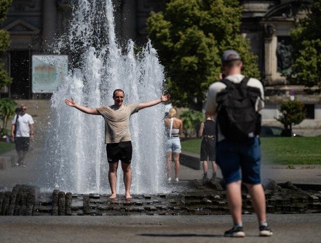 (260730) -- BERLIN, July 30, 2026 (Xinhua) -- A man poses for photos in a fountain in Berlin, capital of Germany, July 30, 2026. Germany recorded an estimated 9,800 heat-related deaths as of July 19, surpassing the annual total for every year since 2016, the Robert Koch Institute (RKI), the country's leading public health authority, said Thursday. (Xinhua/Zhang Haofu)