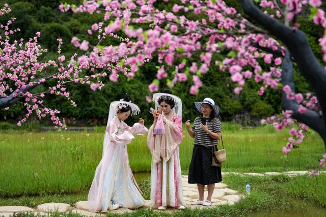 (260731) -- WENSHAN, July 31, 2026 (Xinhua) -- Tourists dressed in traditional Chinese costumes prepare for photos at the Puzhehei scenic area in Qiubei County, Wenshan Zhuang and Miao Autonomous Prefecture, southwest China's Yunnan Province, on July 30, 2026. The Puzhehei scenic area has seen an increased number of tourists during the country's summer peak tourism season. (Xinhua/Chen Xinbo)