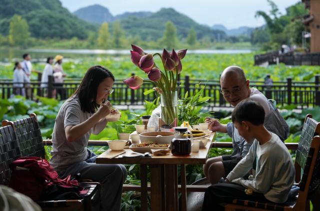 (260731) -- WENSHAN, July 31, 2026 (Xinhua) -- Tourists enjoy a meal at the Xianrendong Village within the Puzhehei scenic area in Qiubei County, Wenshan Zhuang and Miao Autonomous Prefecture, southwest China's Yunnan Province, on July 30, 2026. The Puzhehei scenic area has seen an increased number of tourists during the country's summer peak tourism season. (Xinhua/Chen Xinbo)