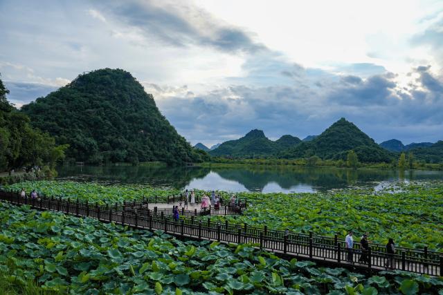 (260731) -- WENSHAN, July 31, 2026 (Xinhua) -- Tourists visit the Xianrendong Village within the Puzhehei scenic area in Qiubei County, Wenshan Zhuang and Miao Autonomous Prefecture, southwest China's Yunnan Province, on July 30, 2026. The Puzhehei scenic area has seen an increased number of tourists during the country's summer peak tourism season. (Xinhua/Chen Xinbo)