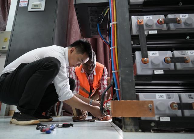 (260731) -- NAIROBI, July 31, 2026 (Xinhua) -- Communication engineer Zhou Junbing guides a local staff member on backup power replacement for the communication system at Mtito Andei Station on the Mombasa-Nairobi Standard Gauge Railway in Kenya on July 23, 2026. After graduating from Beijing Jiaotong University with a degree in communication engineering, Zhou Junbing joined the Africa Star Railway Operation Company (Afristar) at the age of 27, dedicating himself to the operation of Mombasa-Nairobi Standard Gauge Railway (SGR). 
  At that time, the railway had just begun operations. Thanks to Zhou's solid expertise and experience in railway communication, he quickly became a key member of a team responsible for maintaining and supporting the railway's communication system. 
  The railway stretches 472 km, linking the port city of Mombasa in the southeastern part of the country with the capital city, Nairobi. It is the first modern railway constructed in Kenya since independence and stands as a key achievement of China-Kenya cooperation under the Belt and Road Initiative. The Afristar provides operational and technical support for the Mombasa-Nairobi SGR.
  Today, Zhou is in charge of the technical support for communication equipment serving 26 railway systems along the Mombasa-Nairobi SGR. He spends much of his time on the front line of equipment maintenance and technical support. During his eight years working in Kenya, Zhou has continuously shared his expertise with local employees. Whenever the local staff encounter technical challenges, Zhou is always the first person they turn to for advice. To his Kenyan colleagues, Zhou is not only a Chinese engineer, but also a trusted mentor and friend. (Xinhua/Yang Guang)