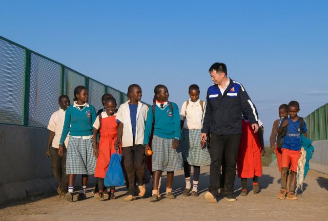 (260731) -- NAIROBI, July 31, 2026 (Xinhua) -- Communication engineer Zhou Junbing talks with local children at a railway station on the Mombasa-Nairobi Standard Gauge Railway in Kenya on July 24, 2026. After graduating from Beijing Jiaotong University with a degree in communication engineering, Zhou Junbing joined the Africa Star Railway Operation Company (Afristar) at the age of 27, dedicating himself to the operation of Mombasa-Nairobi Standard Gauge Railway (SGR). 
  At that time, the railway had just begun operations. Thanks to Zhou's solid expertise and experience in railway communication, he quickly became a key member of a team responsible for maintaining and supporting the railway's communication system. 
  The railway stretches 472 km, linking the port city of Mombasa in the southeastern part of the country with the capital city, Nairobi. It is the first modern railway constructed in Kenya since independence and stands as a key achievement of China-Kenya cooperation under the Belt and Road Initiative. The Afristar provides operational and technical support for the Mombasa-Nairobi SGR.
  Today, Zhou is in charge of the technical support for communication equipment serving 26 railway systems along the Mombasa-Nairobi SGR. He spends much of his time on the front line of equipment maintenance and technical support. During his eight years working in Kenya, Zhou has continuously shared his expertise with local employees. Whenever the local staff encounter technical challenges, Zhou is always the first person they turn to for advice. To his Kenyan colleagues, Zhou is not only a Chinese engineer, but also a trusted mentor and friend. (Xinhua/Yang Guang)