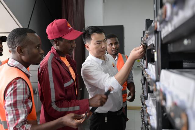 (260731) -- NAIROBI, July 31, 2026 (Xinhua) -- Communication engineer Zhou Junbing guides local staff members on backup power replacement for the communication system at Mtito Andei Station on the Mombasa-Nairobi Standard Gauge Railway in Kenya on July 23, 2026. After graduating from Beijing Jiaotong University with a degree in communication engineering, Zhou Junbing joined the Africa Star Railway Operation Company (Afristar) at the age of 27, dedicating himself to the operation of Mombasa-Nairobi Standard Gauge Railway (SGR). 
  At that time, the railway had just begun operations. Thanks to Zhou's solid expertise and experience in railway communication, he quickly became a key member of a team responsible for maintaining and supporting the railway's communication system. 
  The railway stretches 472 km, linking the port city of Mombasa in the southeastern part of the country with the capital city, Nairobi. It is the first modern railway constructed in Kenya since independence and stands as a key achievement of China-Kenya cooperation under the Belt and Road Initiative. The Afristar provides operational and technical support for the Mombasa-Nairobi SGR.
  Today, Zhou is in charge of the technical support for communication equipment serving 26 railway systems along the Mombasa-Nairobi SGR. He spends much of his time on the front line of equipment maintenance and technical support. During his eight years working in Kenya, Zhou has continuously shared his expertise with local employees. Whenever the local staff encounter technical challenges, Zhou is always the first person they turn to for advice. To his Kenyan colleagues, Zhou is not only a Chinese engineer, but also a trusted mentor and friend. (Xinhua/Yang Guang)
