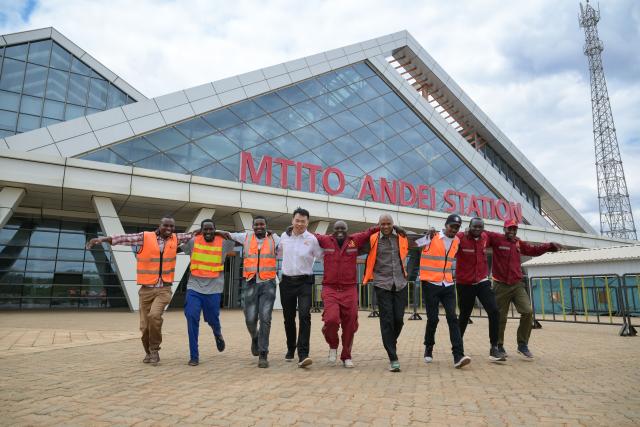 (260731) -- NAIROBI, July 31, 2026 (Xinhua) -- Communication engineer Zhou Junbing (4th L) poses for photos with local staff members at Mtito Andei Station on the Mombasa-Nairobi Standard Gauge Railway in Kenya on July 23, 2026.
  After graduating from Beijing Jiaotong University with a degree in communication engineering, Zhou Junbing joined the Africa Star Railway Operation Company (Afristar) at the age of 27, dedicating himself to the operation of Mombasa-Nairobi Standard Gauge Railway (SGR). 
  At that time, the railway had just begun operations. Thanks to Zhou's solid expertise and experience in railway communication, he quickly became a key member of a team responsible for maintaining and supporting the railway's communication system. 
  The railway stretches 472 km, linking the port city of Mombasa in the southeastern part of the country with the capital city, Nairobi. It is the first modern railway constructed in Kenya since independence and stands as a key achievement of China-Kenya cooperation under the Belt and Road Initiative. The Afristar provides operational and technical support for the Mombasa-Nairobi SGR.
  Today, Zhou is in charge of the technical support for communication equipment serving 26 railway systems along the Mombasa-Nairobi SGR. He spends much of his time on the front line of equipment maintenance and technical support. During his eight years working in Kenya, Zhou has continuously shared his expertise with local employees. Whenever the local staff encounter technical challenges, Zhou is always the first person they turn to for advice. To his Kenyan colleagues, Zhou is not only a Chinese engineer, but also a trusted mentor and friend. (Xinhua/Yang Guang)