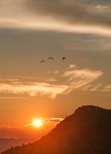 (260731) -- HUANGPING, July 31, 2026 (Xinhua) -- A drone photo taken on July 30, 2026 shows tourists experiencing paragliding with pilots at a paragliding base in Jiuzhou Town, Huangping County, southwest China's Guizhou Province. During the summer vacation, visitors head to the paragliding base here, where they soar over the mountains with professional pilots and enjoy the cool mountain air. (Photo by Liang Wen/Xinhua)
