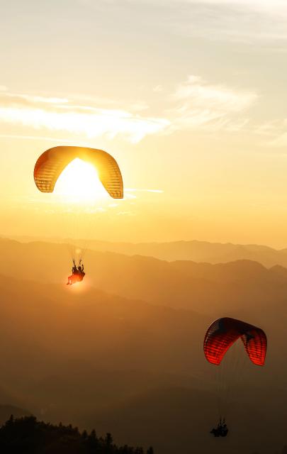 (260731) -- HUANGPING, July 31, 2026 (Xinhua) -- An aerial photo taken on July 30, 2026 shows tourists experiencing paragliding with pilots at a paragliding base in Jiuzhou Town, Huangping County, southwest China's Guizhou Province. During the summer vacation, visitors head to the paragliding base here, where they soar over the mountains with professional pilots and enjoy the cool mountain air. (Xinhua/Yang Wenbin)