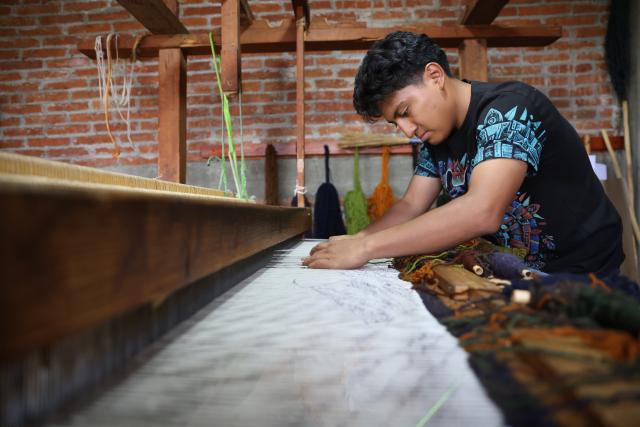 (260731) -- OAXACA, July 31, 2026 (Xinhua) -- Artisan Neri David Gonzalez weaves a wool rug at a textile workshop in Teotitlan del Valle, Oaxaca State, Mexico, July 28, 2026. The southern Mexican state of Oaxaca is known for its handwoven textiles and embroidered garments. Local artisans make clothing, rugs and other items using weaving, dyeing and embroidery techniques. Sold at markets and handicraft fairs, these colorful creations remain part of everyday life in Oaxaca. (Xinhua/Liu Wenhui)