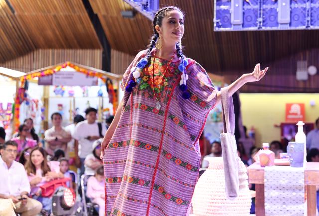 (260731) -- OAXACA, July 31, 2026 (Xinhua) -- A model presents a handwoven and embroidered garment at the 2026 Guelaguetza Handicrafts Fair in Oaxaca City, Oaxaca State, Mexico, July 26, 2026. The southern Mexican state of Oaxaca is known for its handwoven textiles and embroidered garments. Local artisans make clothing, rugs and other items using weaving, dyeing and embroidery techniques. Sold at markets and handicraft fairs, these colorful creations remain part of everyday life in Oaxaca. (Xinhua/Liu Wenhui)