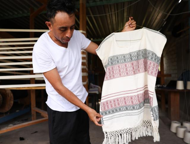 (260731) -- OAXACA, July 31, 2026 (Xinhua) -- An artisan displays his work at his family's textile workshop in San Pablo Villa de Mitla, Oaxaca State, Mexico, July 28, 2026. The southern Mexican state of Oaxaca is known for its handwoven textiles and embroidered garments. Local artisans make clothing, rugs and other items using weaving, dyeing and embroidery techniques. Sold at markets and handicraft fairs, these colorful creations remain part of everyday life in Oaxaca. (Xinhua/Liu Wenhui)