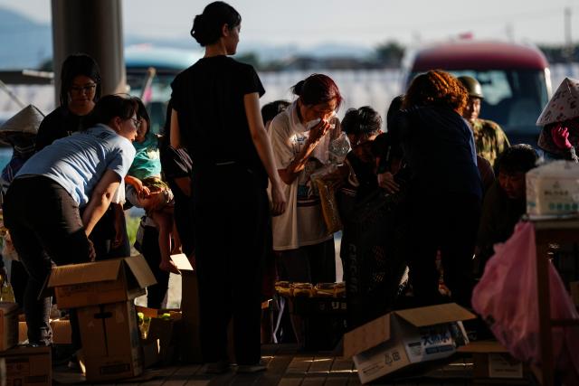 (260731) -- KUMAMOTO, July 31, 2026 (Xinhua) -- People receive relief materials at a shelter in Kumamoto Prefecture, Japan, July 30, 2026. The death toll from a powerful earthquake that struck Japan's Kumamoto Prefecture has risen to 35, the prefectural government said Friday. (Xinhua/Jia Haocheng)