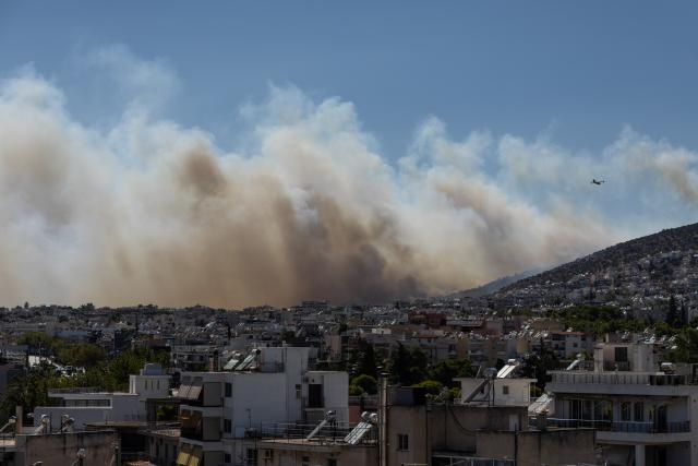 (260731) -- GREECE, July 31, 2026 (Xinhua) -- Wildfire smoke rises from the slopes of Mount Poikilo as seen from the Haidari district of western Athens, Greece, July 31, 2026. Strong winds fueled multiple wildfires across Greece on Friday, forcing hundreds of people to be evacuated by sea while firefighters battled more than 70 wildfires nationwide. (Photo by Lefteris Partsalis/Xinhua)