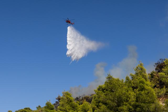 (260731) -- GREECE, July 31, 2026 (Xinhua) -- A firefighting aircraft drops water over wildfire on the slopes of Mount Poikilo in the Haidari district of western Athens, Greece, July 31, 2026. Strong winds fueled multiple wildfires across Greece on Friday, forcing hundreds of people to be evacuated by sea while firefighters battled more than 70 wildfires nationwide. (Photo by Lefteris Partsalis/Xinhua)