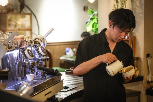 (260802) -- SHENYANG, Aug. 2, 2026 (Xinhua) -- A barista prepares coffee at a coffee shop on Bajing Street, Shenyang City, northeast China's Liaoning Province, Aug. 1, 2026. A pack of coffee shops of varying styles on Bajing Street in Shenyang have breathed new life into the old city. Once quiet but obsolete, this historic street is now a vibrant new landmark of culture and tourism that attracts thousands of young visitors every day. Each coffee shop here tells a different story of how a city grows in time. (Xinhua/Pan Yulong)