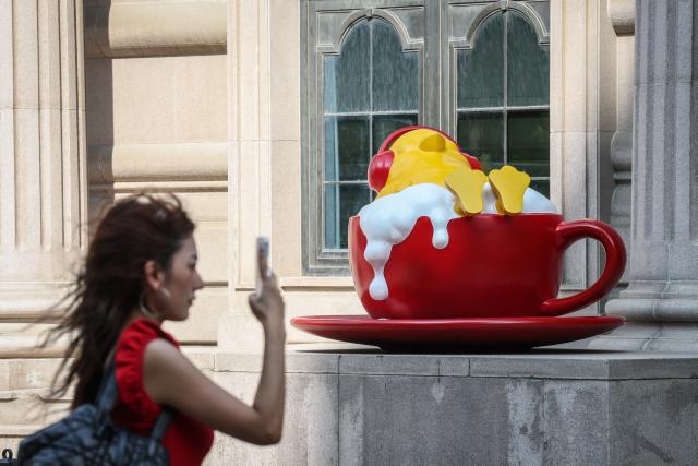 (260802) -- SHENYANG, Aug. 2, 2026 (Xinhua) -- A tourist walks past an installation on Bajing Street, Shenyang City, northeast China's Liaoning Province, Aug. 1, 2026. A pack of coffee shops of varying styles on Bajing Street in Shenyang have breathed new life into the old city. Once quiet but obsolete, this historic street is now a vibrant new landmark of culture and tourism that attracts thousands of young visitors every day. Each coffee shop here tells a different story of how a city grows in time. (Xinhua/Pan Yulong)