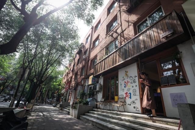 (260802) -- SHENYANG, Aug. 2, 2026 (Xinhua) -- A customer walks out a coffee shop on Bajing Street, Shenyang City, northeast China's Liaoning Province, Aug. 1, 2026. A pack of coffee shops of varying styles on Bajing Street in Shenyang have breathed new life into the old city. Once quiet but obsolete, this historic street is now a vibrant new landmark of culture and tourism that attracts thousands of young visitors every day. Each coffee shop here tells a different story of how a city grows in time. (Xinhua/Pan Yulong)