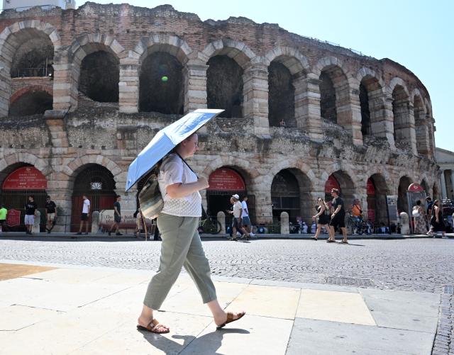 (260802) -- VERONA, Aug. 2, 2026 (Xinhua) -- A tourist shields herself from the sun with an umbrella near the Arena di Verona in Verona, Italy, Aug. 2, 2026. (Photo by Alberto Lingria/Xinhua)