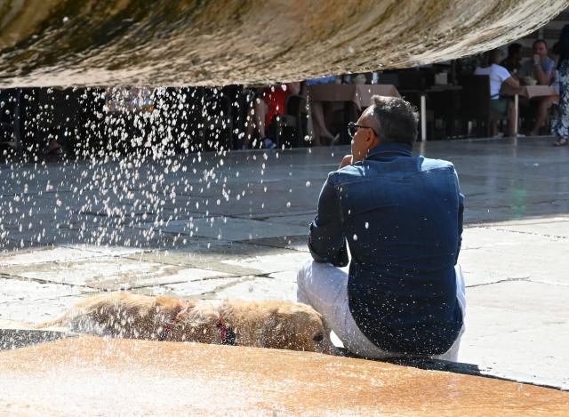 (260802) -- VERONA, Aug. 2, 2026 (Xinhua) -- A man and his dog cool off near a fountain in Verona, Italy, Aug. 2, 2026. (Photo by Alberto Lingria/Xinhua)