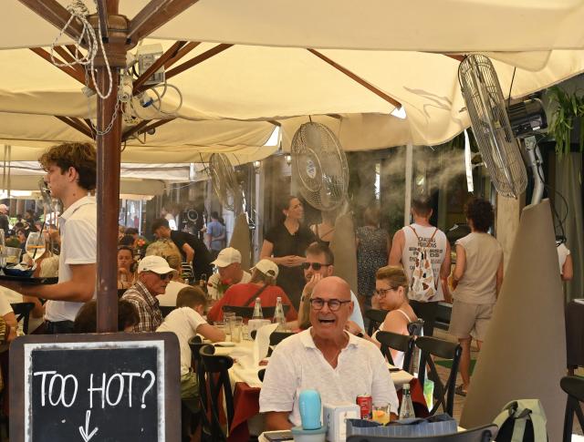 (260802) -- VERONA, Aug. 2, 2026 (Xinhua) -- Tourists have lunch with fans to cool off in Verona, Italy, Aug. 2, 2026. (Photo by Alberto Lingria/Xinhua)