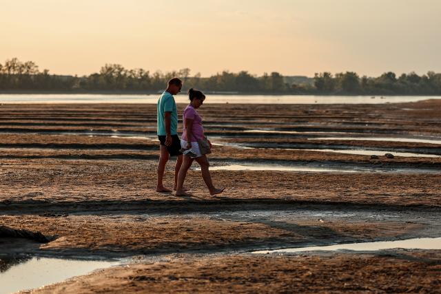 (260803) -- BUDAPEST, Aug. 3, 2026 (Xinhua) -- People walk on the exposed riverbed of the Danube River in Dunaszentbenedek, Hungary, Aug. 2, 2026. Hungary is entering its "most critical 5 days" as dropping water levels on the Danube River threaten the complete shutdown of the Paks nuclear power plant amid an extreme heatwave, Hungary's Prime Minister Peter Magyar said on Sunday, warning that the plant could be shut down for more than a month. (Photo by David Balogh/Xinhua)