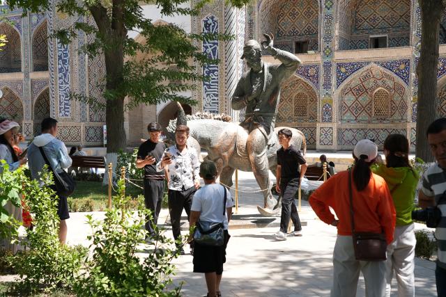 (260803) -- BUKHARA, Aug. 3, 2026 (Xinhua) -- Tourists take photos around the Statue of Hodja Nasreddin in Bukhara, Uzbekistan, Aug. 3, 2026. The historic city of Bukhara in southwestern Uzbekistan is currently gripping with severe heat, with daytime highs consecutively exceeding 35 degrees Celsius. (Photo by Zafar Khalilov/Xinhua)