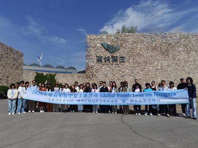 (260804) -- YINCHUAN, Aug. 4, 2026 (Xinhua) -- A group of overseas students and local staff members pose for a photo at a vineyard in Qingtongxia of Wuzhong, northwest China's Ningxia Hui Autonomous Region, on July 15, 2026. TO GO WITH "Across China: From barren land, a wine region takes root" (Xinhua/Xie Jianwen)