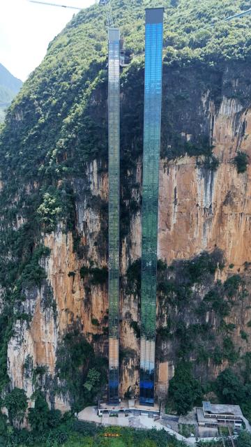 (260804) -- XUANWEI, Aug. 4, 2026 (Xinhua) -- An aerial drone photo taken on July 31, 2026 shows two cliff elevators at Nizhu River Grand Canyon in Nizhuhe Village of Puli Township, Xuanwei City, southwest China's Yunnan Province. A 288-meter-high cliff elevator began operation recently at Nizhu River Grand Canyon, side by side to another one of its kind already in service since 2022. This is expected to further facilitate local students' trips to their schools. 
   Nizhuhe Village is a small hamlet nestled in a deep valley carved by the Nizhu River meandering from south to north. In the past, the shortest route from the valley floor to the mountaintop was a steep cliffside path, and the round trip took nearly six hours. Children and their parents had to make the arduous journey at least once every 10 days.
   In 2022, a significant change came to this challenging journey. Nizhu River Grand Canyon scenic area was completed and opened, with a 268-meter-high cliff elevator and a cable car system put into operation. The facilities are open free of charge to local villagers.
   Today, the combination of sightseeing shuttle vehicles, elevators and cable cars has shortened students' journey to school to about 30 minutes. A dedicated passage has also been set up for the students, with police officers and dedicated staff members as their guardians along the trips. (Xinhua)