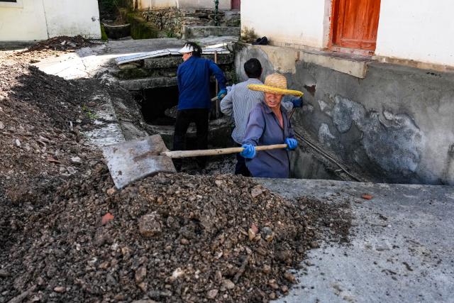 (260804) -- KANGXIAN, Aug. 4, 2026 (Xinhua) -- Villagers remove mud and gravel from a drainage ditch at Jiedao Village of Kangxian County in Longnan City, northwest China's Gansu Province, Aug. 4, 2026. Kangxian, which suffered from heavy rainfall recently, has initiated campaigns to clear up rivers and restore drinking water facilities in the county, striving to bring people's work and daily life back to normal. (Xinhua/Lang Bingbing)