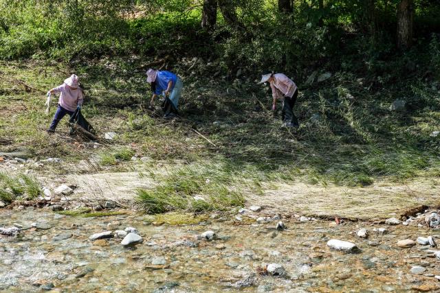 (260804) -- KANGXIAN, Aug. 4, 2026 (Xinhua) -- Villagers remove garbage and debris from the riverbank at Zhangjiahe Village of Kangxian County in Longnan City, northwest China's Gansu Province, Aug. 4, 2026. Kangxian, which suffered from heavy rainfall recently, has initiated campaigns to clear up rivers and restore drinking water facilities in the county, striving to bring people's work and daily life back to normal. (Xinhua/Lang Bingbing)