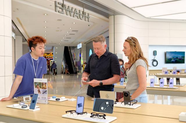 (260804) -- SHANGHAI, Aug. 4, 2026 (Xinhua) -- Foreign tourists select products at a Huawei flagship store in Beijing, capital of China, April 30, 2026. (Xinhua/Ju Huanzong)