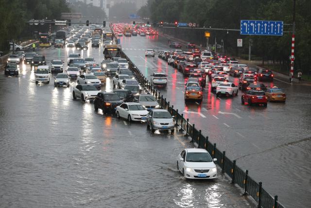 (260804) -- HARBIN, Aug. 4, 2026 (Xinhua) -- Vehicles move on a waterlogged street in Harbin, northeast China's Heilongjiang Province, Aug. 4, 2026. A heavy rain swept the city of Harbin on Tuesday. (Xinhua/Wang Song)