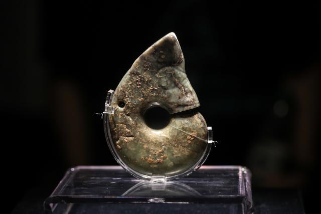 (260804) -- CHAOYANG, Aug. 4, 2026 (Xinhua) -- This photo taken on Aug. 4, 2026 shows the "jade pig-dragon," a specific type of jade artifact originating from the Hongshan culture dating back roughly 5,000 to 6,000 years, at the Niuheliang site museum within the Niuheliang national archaeological relic site park in Chaoyang City, northeast China's Liaoning Province. The Niuheliang national archaeological relic site park was built on the Niuheliang site, a large-scale prehistoric ritual and burial complex featuring the temple of the goddess, altars and stone tombs. Dating back more than 5,000 years, the site unearthed stone tools, pottery and jade artifacts with dragon, phoenix and human motifs, reflecting the rituals and beliefs of the Hongshan culture. (Xinhua/Pan Yulong)