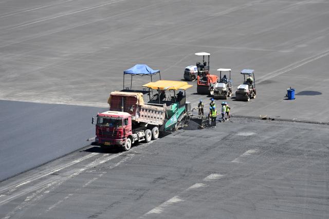(260804) -- ZHANGYE, Aug. 4, 2026 (Xinhua) -- Workers lay asphalt at the construction site of a pumped-storage power station in Zhangye, northwest China's Gansu Province, Aug. 4, 2026. The construction of the power station started in 2022, and all the four 350,000-kW reversible pump-turbine units are expected to be fully put into operation by 2029. (Xinhua/Fan Peishen)