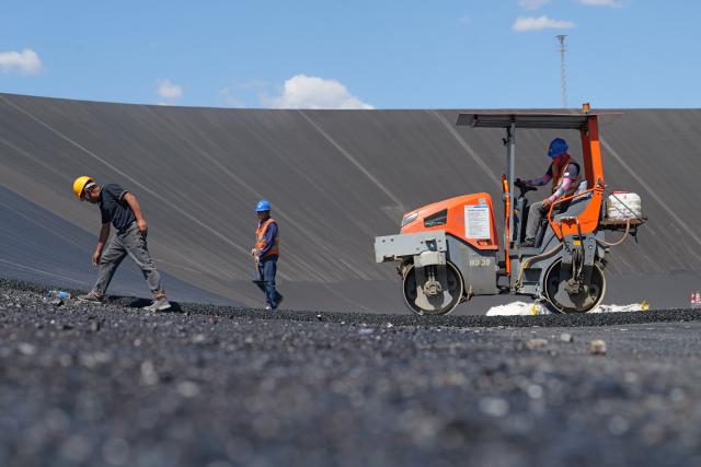 (260804) -- ZHANGYE, Aug. 4, 2026 (Xinhua) -- Workers lay asphalt at the construction site of a pumped-storage power station in Zhangye, northwest China's Gansu Province, Aug. 4, 2026. The construction of the power station started in 2022, and all the four 350,000-kW reversible pump-turbine units are expected to be fully put into operation by 2029. (Xinhua/Liu Keying)