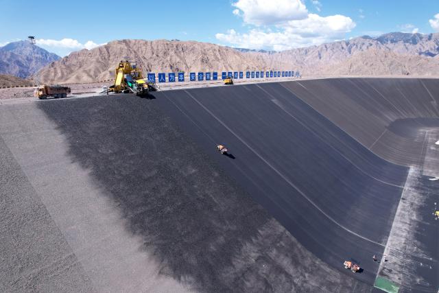 (260804) -- ZHANGYE, Aug. 4, 2026 (Xinhua) -- A drone photo shows workers laying asphalt at the construction site of a pumped-storage power station in Zhangye, northwest China's Gansu Province, Aug. 4, 2026. The construction of the power station started in 2022, and all the four 350,000-kW reversible pump-turbine units are expected to be fully put into operation by 2029. (Xinhua/Fan Peishen)