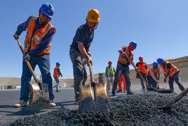 (260804) -- ZHANGYE, Aug. 4, 2026 (Xinhua) -- Workers lay asphalt at the construction site of a pumped-storage power station in Zhangye, northwest China's Gansu Province, Aug. 4, 2026. The construction of the power station started in 2022, and all the four 350,000-kW reversible pump-turbine units are expected to be fully put into operation by 2029. (Xinhua/Liu Keying)