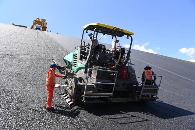(260804) -- ZHANGYE, Aug. 4, 2026 (Xinhua) -- Workers lay asphalt at the construction site of a pumped-storage power station in Zhangye, northwest China's Gansu Province, Aug. 4, 2026. The construction of the power station started in 2022, and all the four 350,000-kW reversible pump-turbine units are expected to be fully put into operation by 2029. (Xinhua/Fan Peishen)