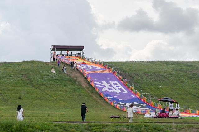 (260804) -- XILIN GOL, Aug. 4, 2026 (Xinhua) -- Tourists play by Baiyin Chagan Lake, or "Milky Lake," in Xilin Gol League, north China's Inner Mongolia Autonomous Region, Aug. 4, 2026. The lake is dubbed "Milky Lake" as tiny mineral particles float in the water, turning it creamy-white like milk. (Xinhua/Lian Zhen)