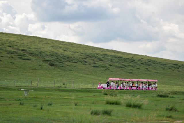 (260804) -- XILIN GOL, Aug. 4, 2026 (Xinhua) -- Tourists play by Baiyin Chagan Lake, or "Milky Lake," in Xilin Gol League, north China's Inner Mongolia Autonomous Region, Aug. 4, 2026. The lake is dubbed "Milky Lake" as tiny mineral particles float in the water, turning it creamy-white like milk. (Xinhua/Lian Zhen)