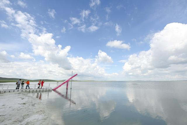 (260804) -- XILIN GOL, Aug. 4, 2026 (Xinhua) -- Tourists visit Baiyin Chagan Lake, or "Milky Lake," in Xilin Gol League, north China's Inner Mongolia Autonomous Region, Aug. 4, 2026. The lake is dubbed "Milky Lake" as tiny mineral particles float in the water, turning it creamy-white like milk. (Xinhua/Lian Zhen)