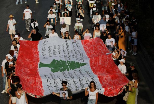 (260804) -- BEIRUT, Aug. 4, 2026 (Xinhua) -- People hold a national flag and portraits of the victims in commemoration of the sixth anniversary of the 2020 Beirut port blasts in Beirut, Lebanon, Aug. 4, 2026. (Xinhua/Bilal Jawich)