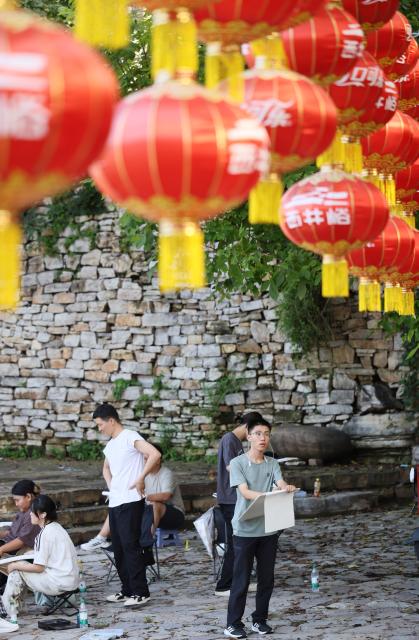 (260805) -- TIANJIN, Aug. 5, 2026 (Xinhua) -- Visitors sketch in Xijingyu Village, Jizhou District of north China's Tianjin Municipality, Aug. 4, 2026. During summer vacation, Xijingyu Village has attracted lots of visitors. Known as the "Stone Village", it is famous for its distinctive houses and alleys built of stones. (Xinhua/Li Ran)